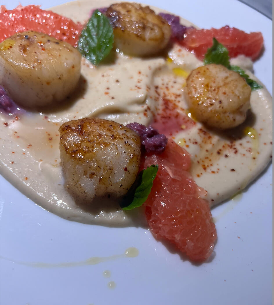 Plate of seared scallops on a bed of sunchoke puree.