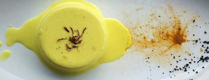 saffron panna cotta on plate with urfa pepper and turmeric garnish